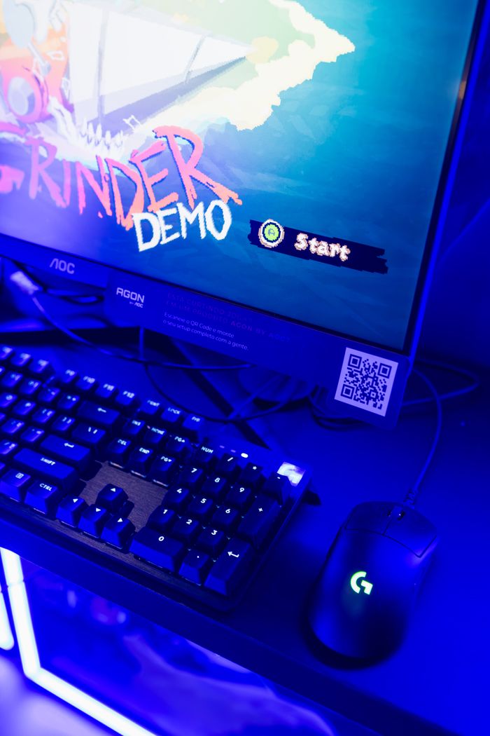 Close-up shot of a gaming setup featuring a keyboard, mouse, and monitor with a QR code and game demo display.