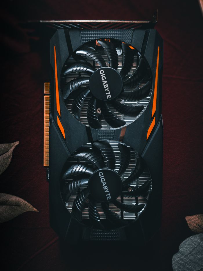 Detailed close-up of a black and orange graphic card with cooling fans.